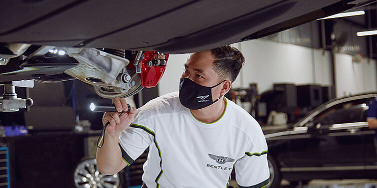 Kỹ thuật viên Bentley kiểm tra gầm xe bằng thiết bị chính hãng trong dịch vụ eVHC tại Bentley Hồ Chí Minh.